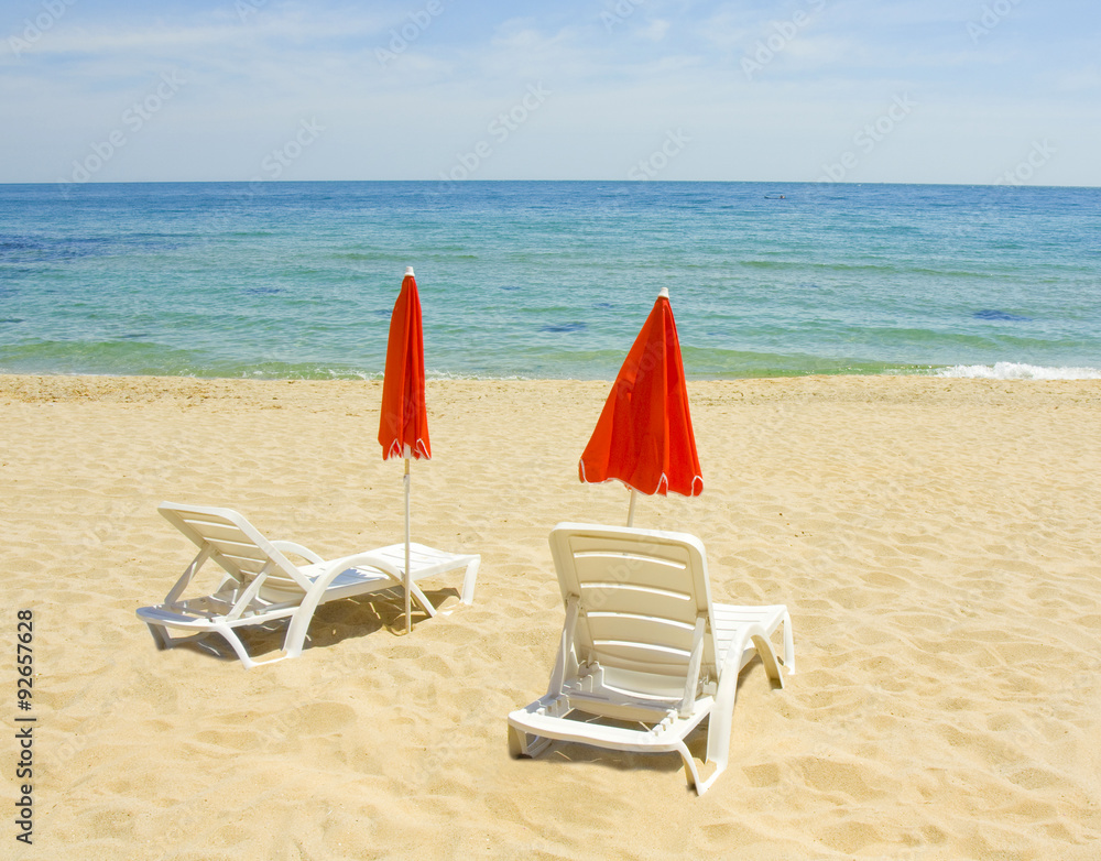 Red beach umbrellas and white chaise longues Red beach umbrellas and white chaise longues