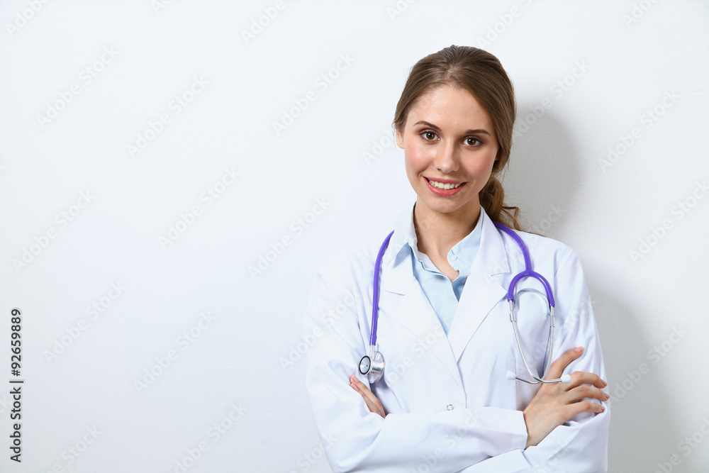 Friendly smiling young female doctor, standing near wall Friendly smiling young female doctor, standing near wall