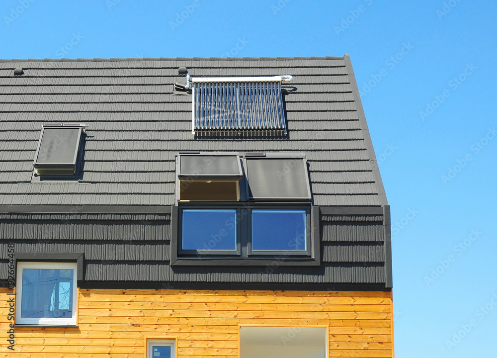 Energy Efficiency New Passive House Building Concept. Closeup of Solar Water Panel Heating, Dormers, Solar Panels, Skylights, Ventilation and Air Conditioning Systems Installed on Tiled House Roof Energy Efficiency New Passive House Building Concept. Closeup of Solar Water Panel Heating, Dormers, Solar Panels, Skylights, Ventilation and Air Conditioning Systems Installed on Tiled House Roof