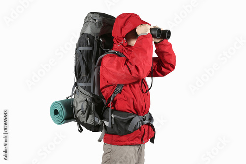 tourist in red jacket with backpack looking through binoculars