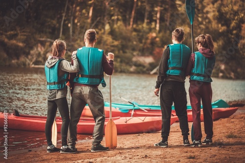 Group of people wearing life jackets near kayaks on a beach