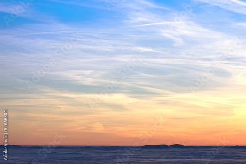 Fototapeta Naklejka Na Ścianę i Meble -  Sunset over the snowy desert. Bright orange blue sky