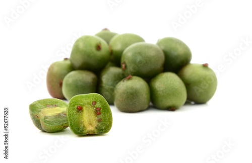 Kiwi berry sliced open in front of pile of berries