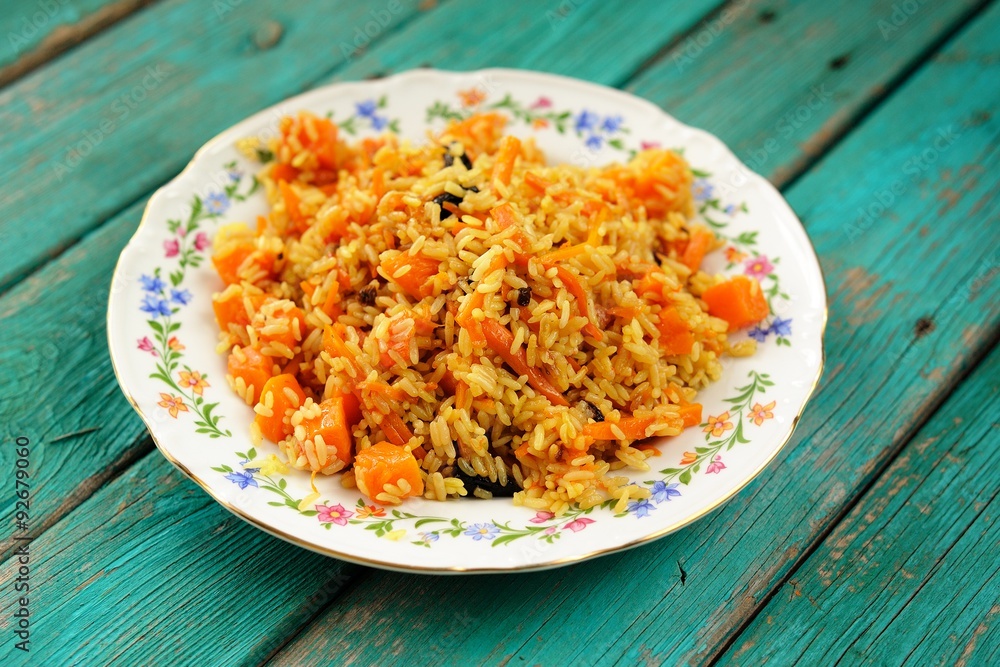Vegetarian pumpkin pilaf in colored plate on wooden turquoise ta Vegetarian pumpkin pilaf in colored plate on wooden turquoise ta