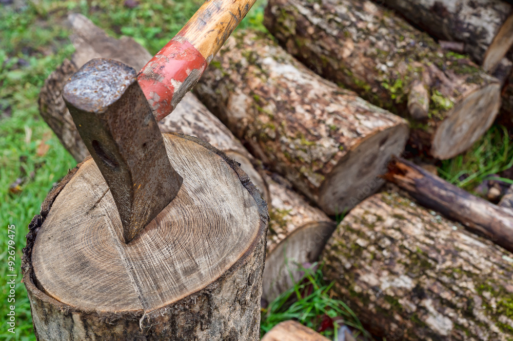 Axe on chopping block with a woodpile in the background Axe on chopping block with a woodpile in the background