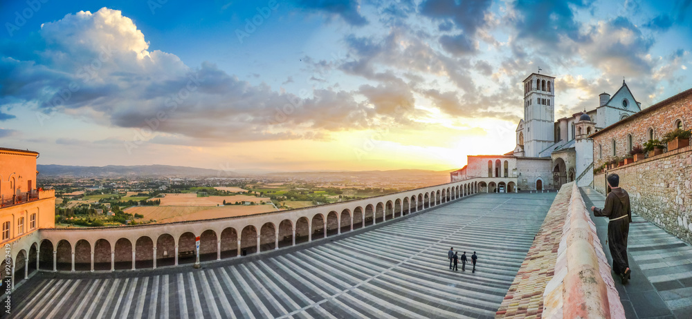 Monk walking towards Basilica St. Francis of Assisi at sunset, Italy