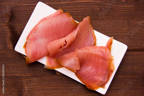 Smoked tuna on small tray on wooden table seen from above