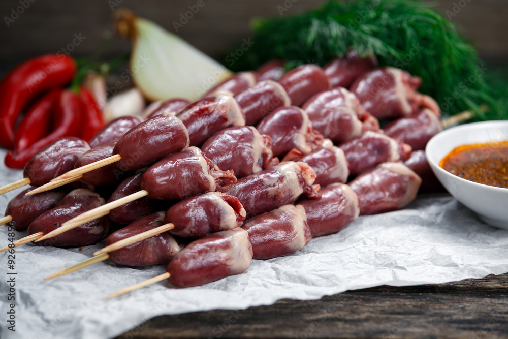 Ready to cook Duck Heart stringed on skewers BBQ with hot sauce and chili pepper. decorated with greens and vegetables. background Ready to cook Duck Heart stringed on skewers BBQ with hot sauce and chili pepper. decorated with greens and vegetables. background