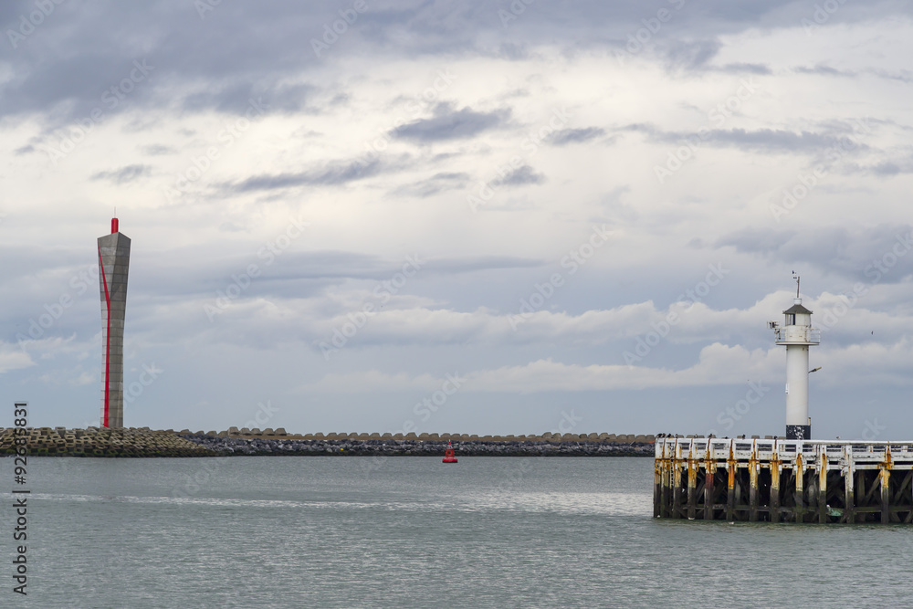 Old-fashioned sea lighthouse and modern radar tower on the