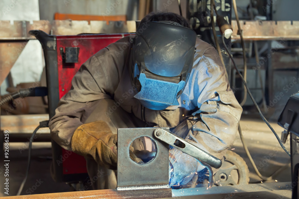 A welder fabricates steel structures using semi-automatic weldin A welder fabricates steel structures using semi-automatic weldin