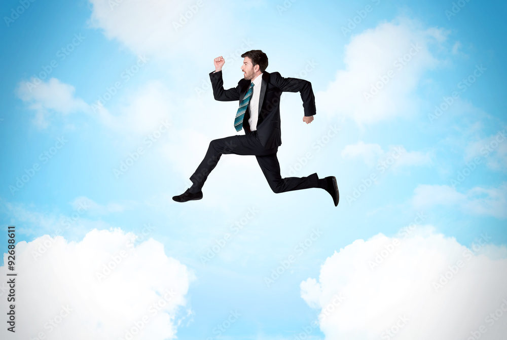 Business person jumping over clouds in the sky Business person jumping over clouds in the sky