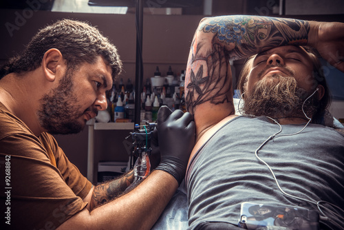Professional tattoo artist showing process of making a tattoo in tattoo studio