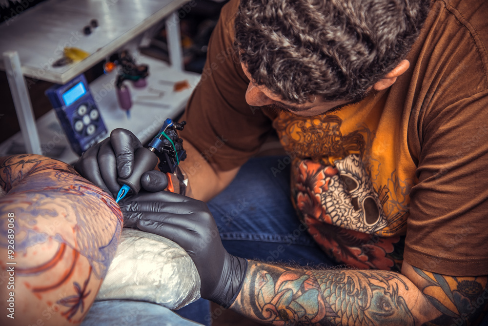 Fototapeta premium Man wearing gloves working tattooing in tattoo studio
