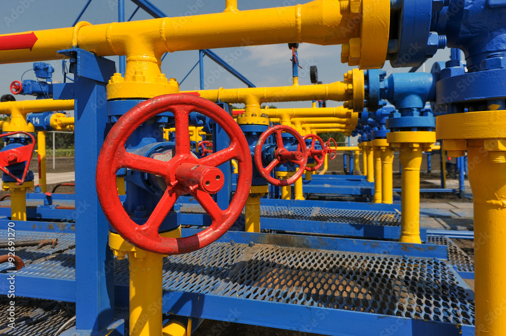 Red faucet with steel pipe in natural gas treatment plant in bright sunny summer day