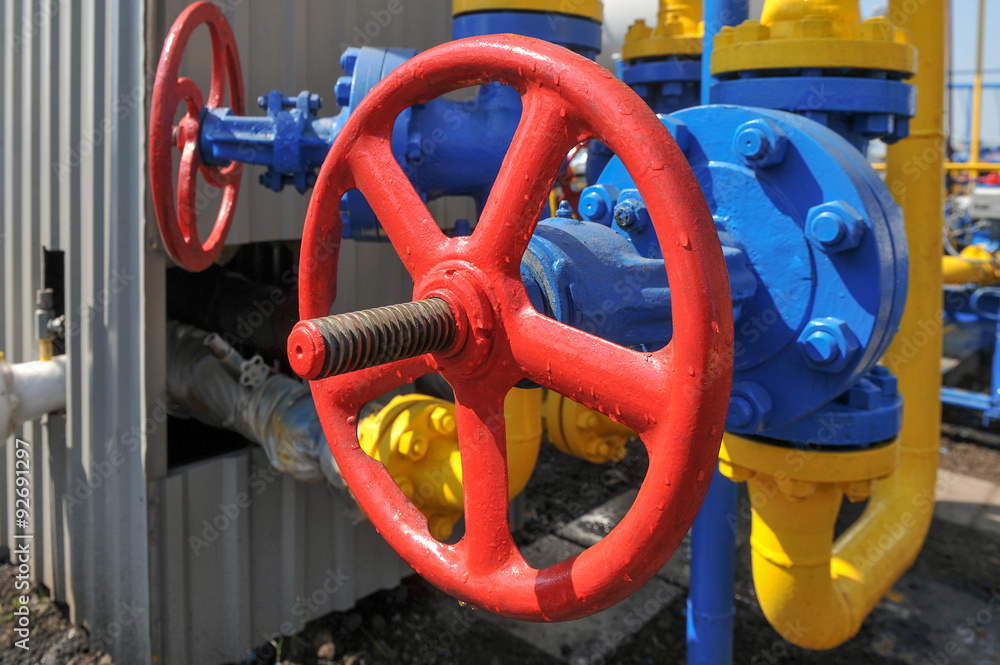 Red faucet with steel pipe in natural gas treatment plant in bright sunny summer day