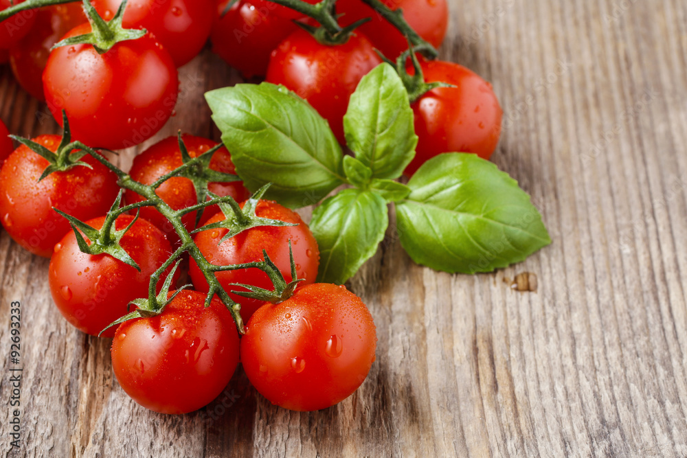 Tomatoes and basil leaves on wooden table Tomatoes and basil leaves on wooden table