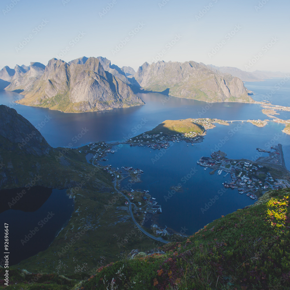 Beautiful norwegian landscape with famous top peak Reinbringen, Lofoten Islands, with a group of hikers tourists, and with a view on famous fishing village Reine, Moskenesoya and norwegian sea

