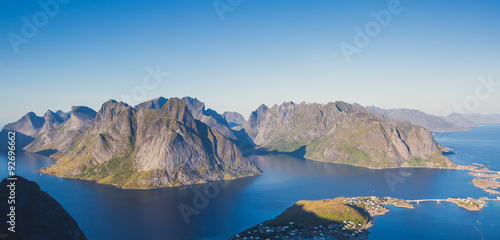 Beautiful norwegian landscape with famous top peak Reinbringen, Lofoten Islands, with a group of hikers tourists, and with a view on famous fishing village Reine, Moskenesoya and norwegian sea 