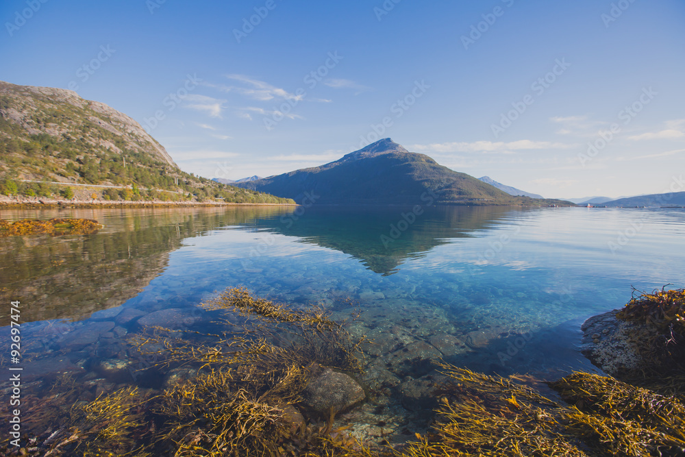 Beautiful vibrant summer norwegian landscape with coast of fjord with a blue sky, blue clear water, norway, norge Beautiful vibrant summer norwegian landscape with coast of fjord with a blue sky, blue clear water, norway, norge