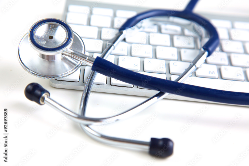 A medical stethoscope near a laptop on a wooden table, on white