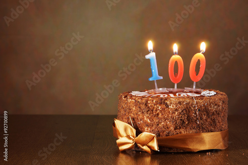 Fotografia Birthday chocolate cake with burning candles as a number one hundred on brown ba