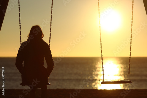 Lonely woman watching sunset alone in winter