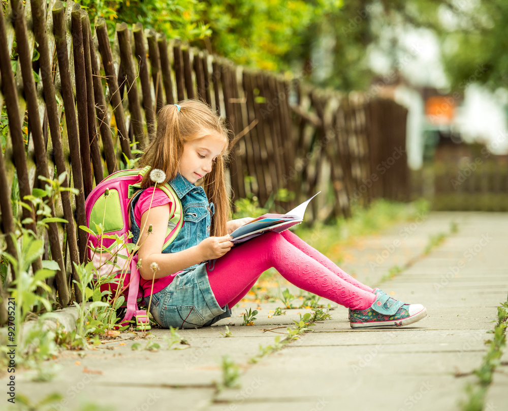 schoolgirl reading a book  on the street