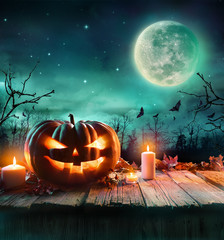 Halloween Pumpkin On Wooden Plank With Candles In A Spooky Night
