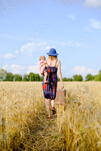 Young mother travelling with her child on hand on the wheat © gorosi