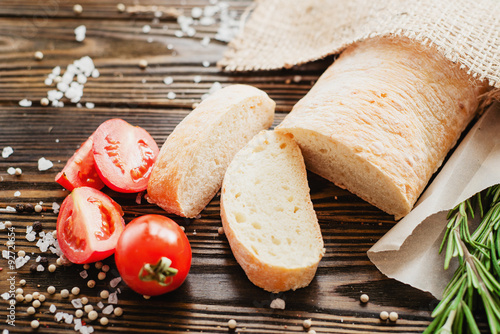  Italian ciabatta with tomatoes , salt, pepper and rosemary on the wooden background