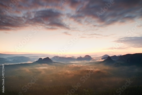 Tourist resort in Saxony. Fantastic dreamy sunrise on the top of the rocky mountain with the view into misty valley