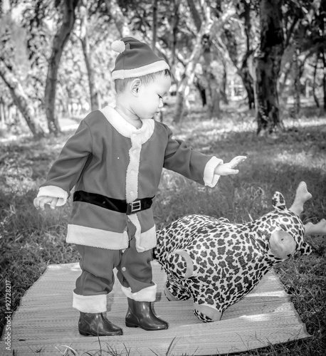 A kid in Santaclaus suit push reindeer doll away , unfriend concept  and black and white photography with vignette   photo