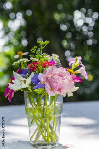 Fototapeta Naklejka Na Ścianę i Meble -  Bouquet flowers in glass vase on outdoor and bokeh background