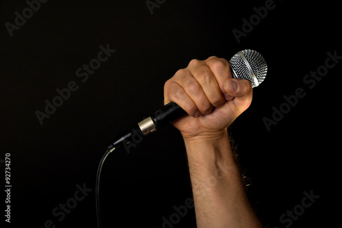 Male hand with microphone isolated on black