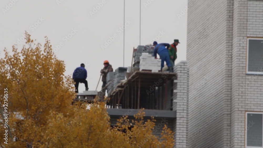 a team of masons building brick multistory house in autumn a team of masons building brick multistory house in autumn