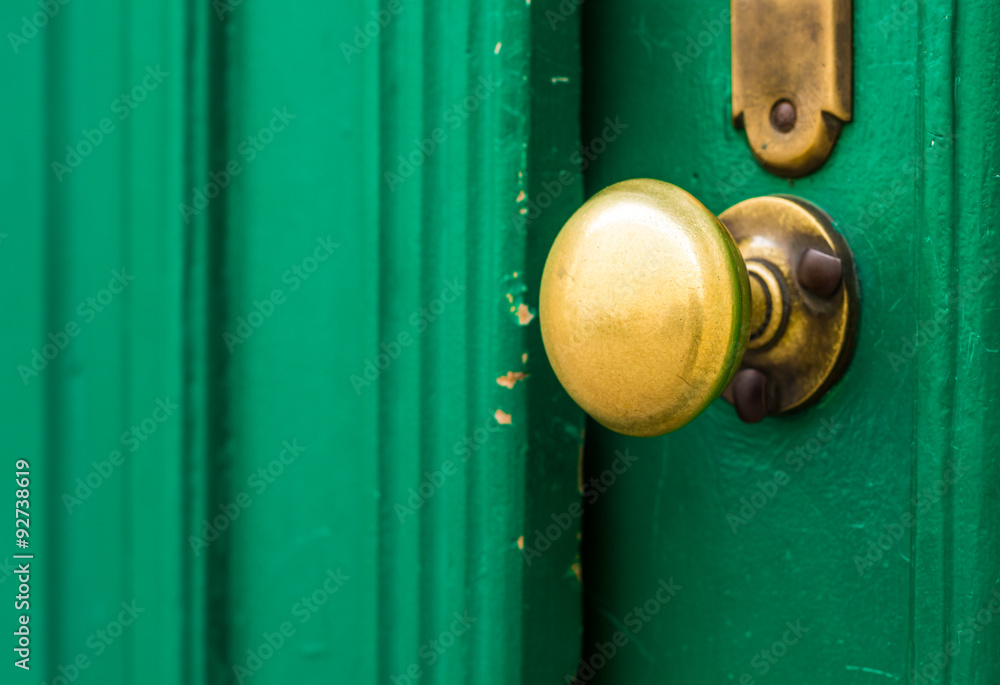 Fototapeta premium Weathered doorknob made of brass on green door