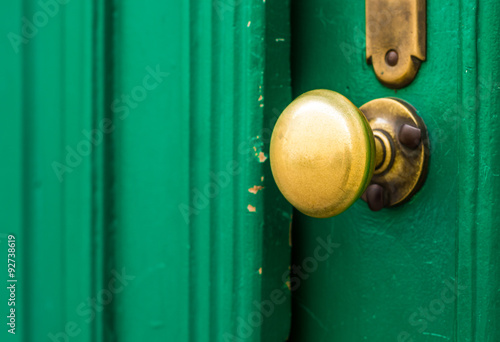 Weathered doorknob made of brass on green door