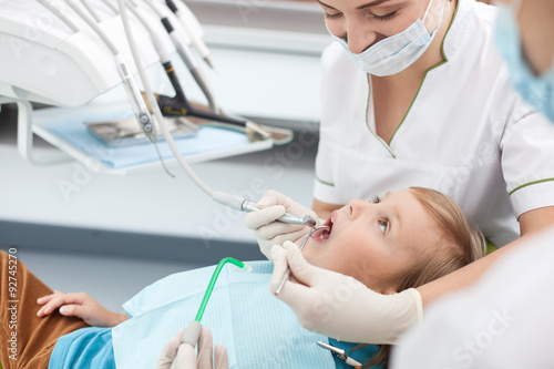 Skillful female dentist is treating small patient photo