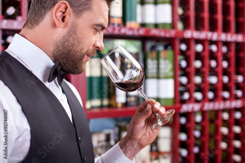 Attractive male sommelier is tasting alcohol drink