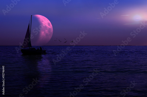 Łódka z żaglem księżyca na jeziorze nocą.