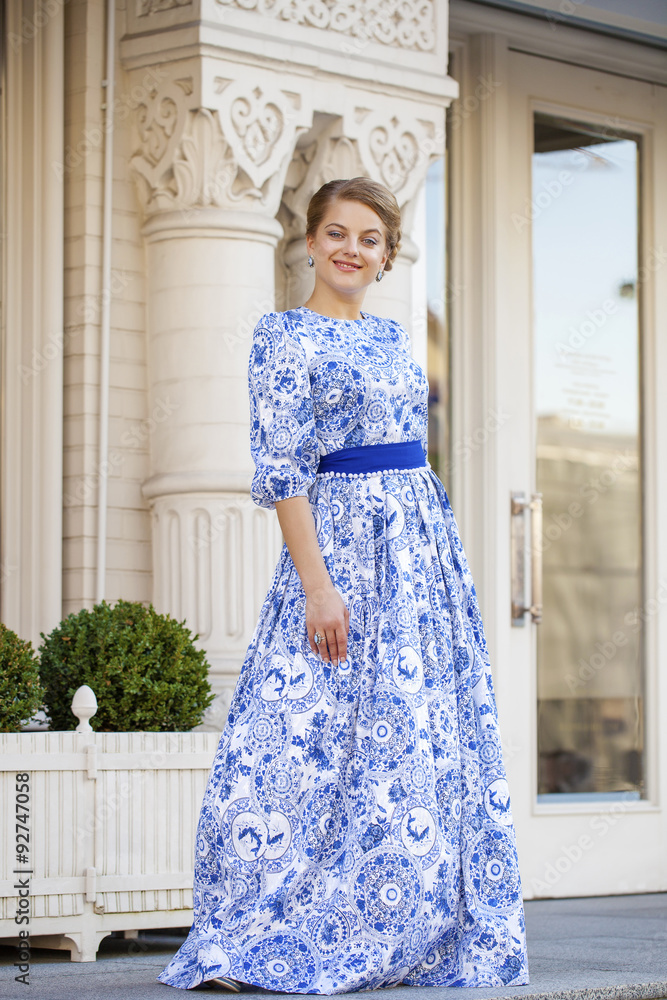 Beautiful blonde girl in blue dress posing against a background Beautiful blonde girl in blue dress posing against a background