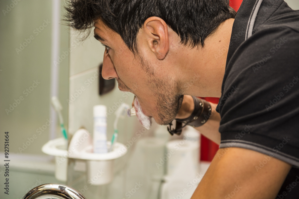 Headshot of attractive young man brushing teeth and tongue Headshot of attractive young man brushing teeth and tongue