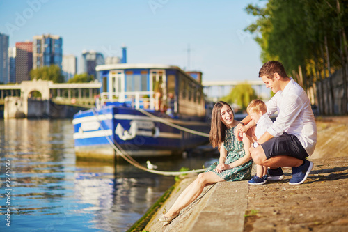 Canvas Print Happy family of three sitting on the bank of the Seine