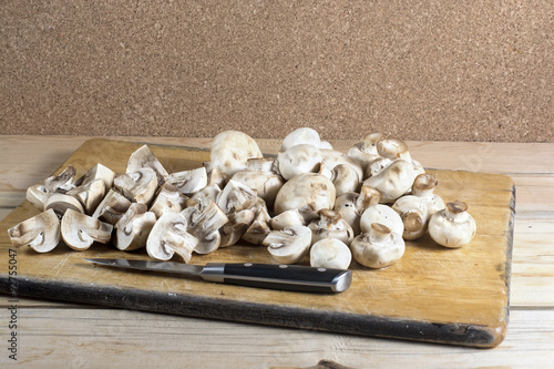 Fresh whole and cutted champignons on a cutting board with a kni photo