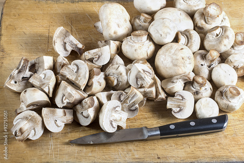 Fresh whole and cutted champignons on a cutting board with a kni photo