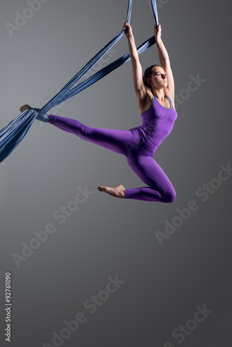 Sporty woman doing exercise with elastics, aerial silk ribbons. Sport training gym and lifestyle concept. Anti-gravity yoga.