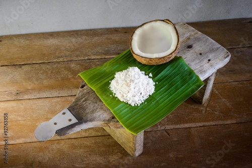 coconuts and coconut flakes on banana leaf and coconut grater