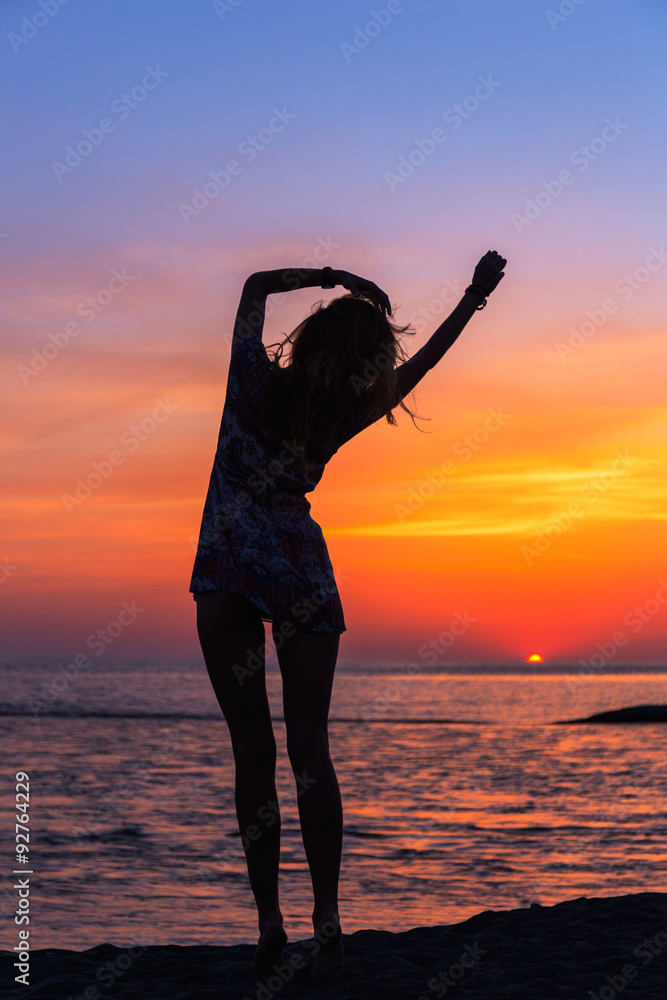 Beautiful young woman on the beach at sunset