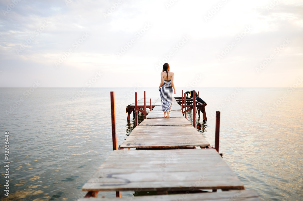 girl in a striped dress walking on a wooden bridge in the backgr girl in a striped dress walking on a wooden bridge in the backgr