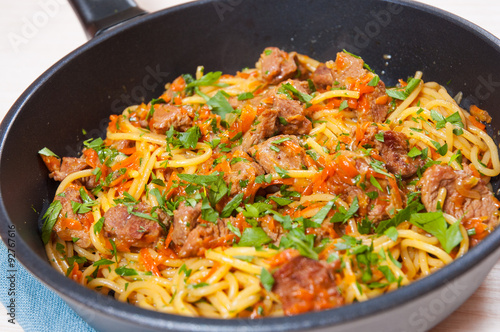 Pieces of meat and vegetables with spaghetti in a frying pan